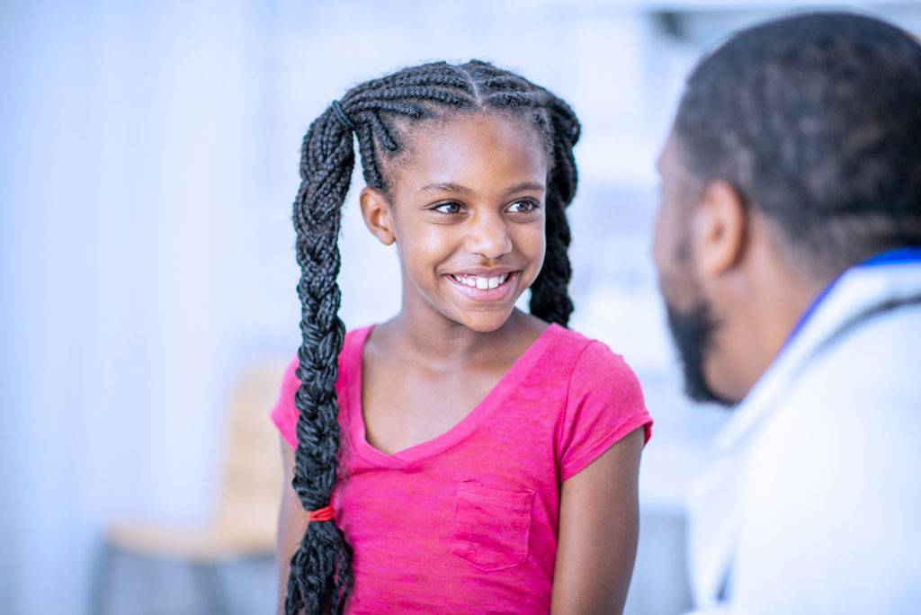 Photo of a girl with clear skin smiling at her male doctor.