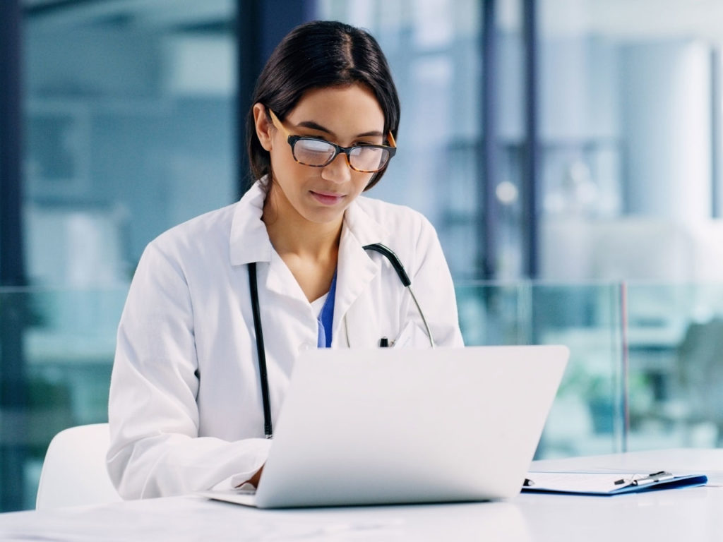 Doctor working on a laptop computer to authorize refill codes for a patient's home phototherapy device.