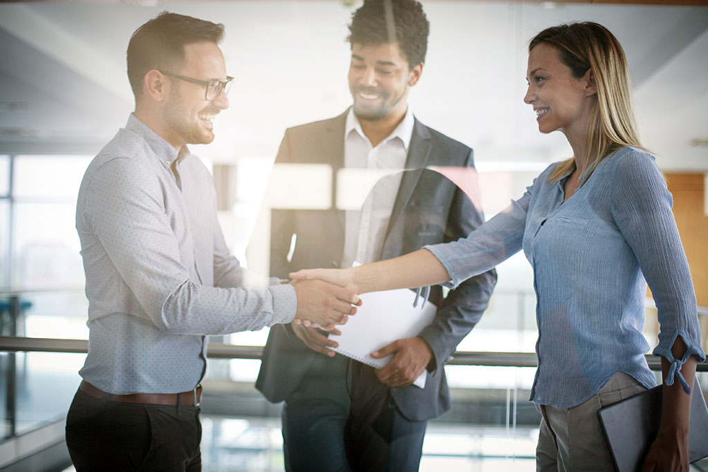 Three professional executives shaking hands in agreement.